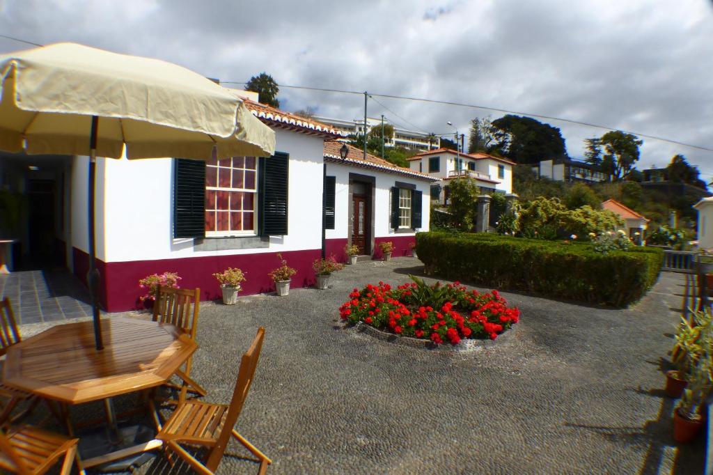 uma casa com um pátio com cadeiras e flores em Casa da Avó Benvinda no Funchal