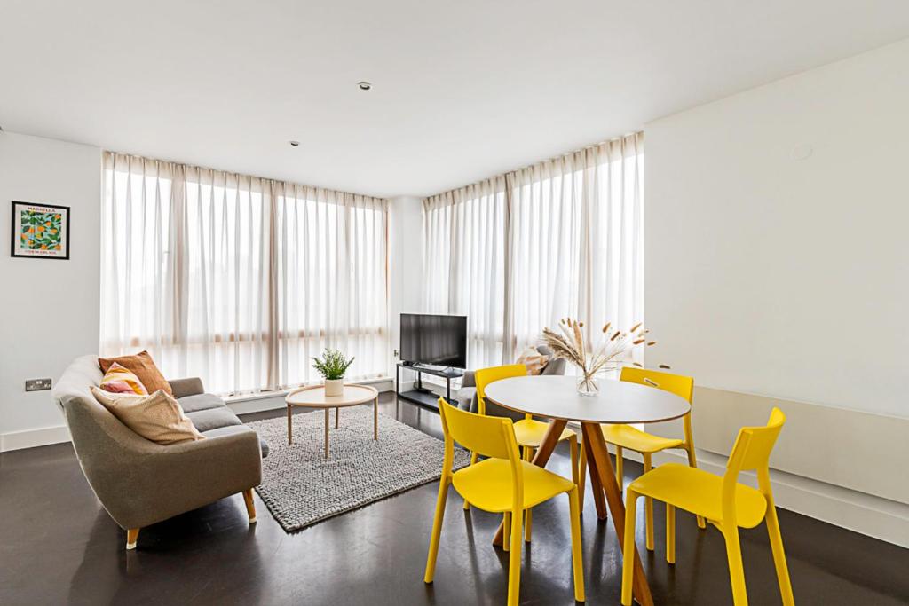 a living room with yellow chairs and a table at Comfortable Modern Flat in Shoreditch in London