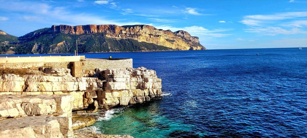 a large body of water next to a rocky cliff at Camping Aux Portes De Cassis in La Bédoule