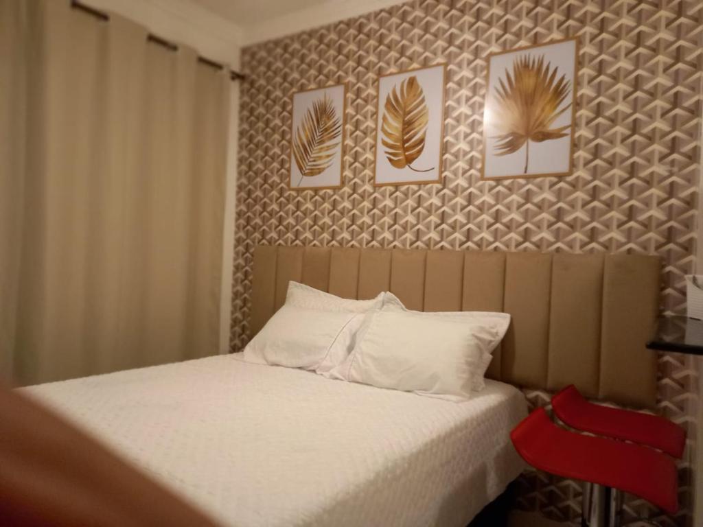 um quarto com uma cama com quatro fotografias na parede em Suíte Studio 3 Enseada Tortuga Mobiliada no Guarujá