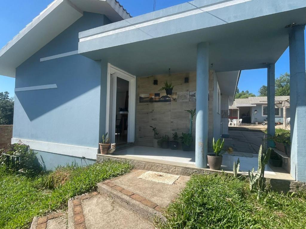 una casa azul con un porche con plantas en Pousada Munhoz, en São Gabriel