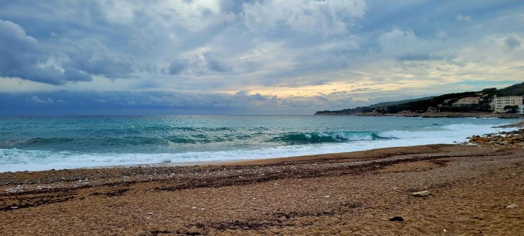 a beach with a cloudy sky and the ocean at Camping Aux Portes De Cassis in La Bédoule