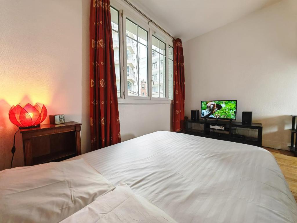 une chambre avec un grand lit blanc et une télévision dans l'établissement 1 mois minimum - Appartement Porte Saint Cloud - Parc des Princes, à Boulogne-Billancourt
