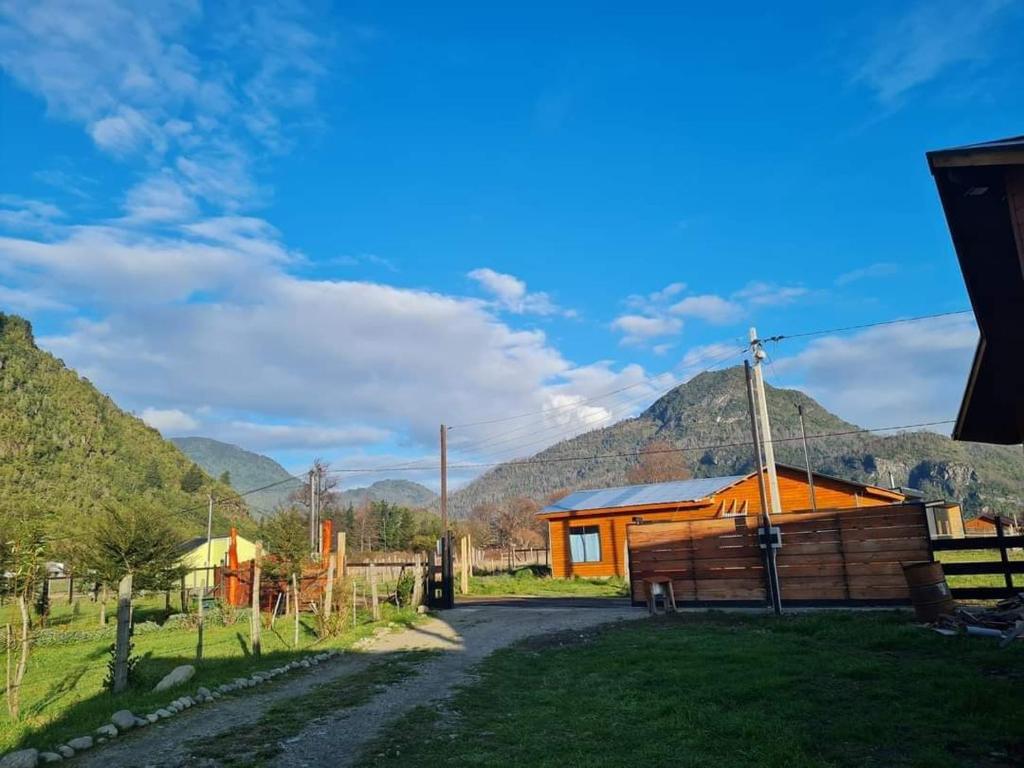 uma cabana num campo com montanhas ao fundo em Cabañas Villa Elfo em Futrono