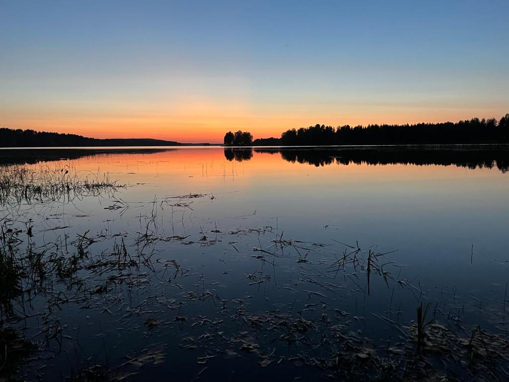 een grote hoeveelheid water met een zonsondergang op de achtergrond bij Kajaani Cottages in Kajaani