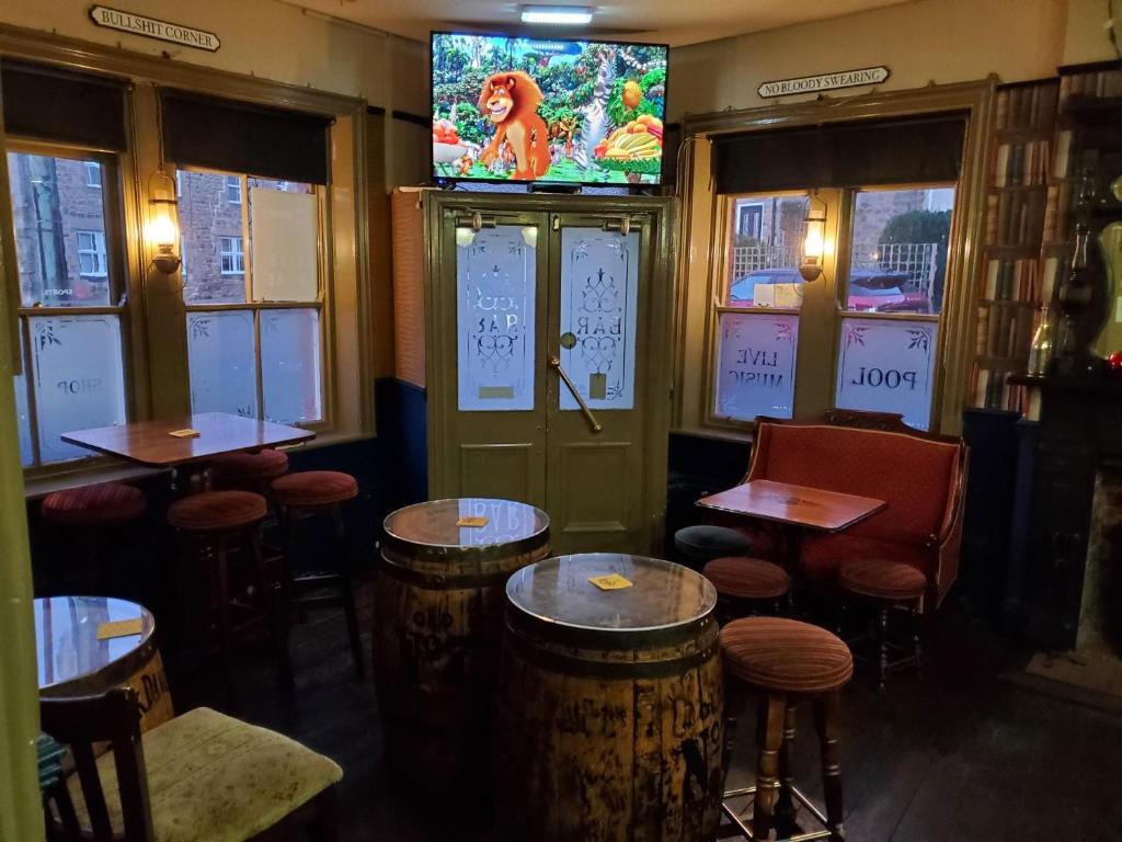 a bar with tables and a tv on the wall at The Queens Arms Hotel in Acomb