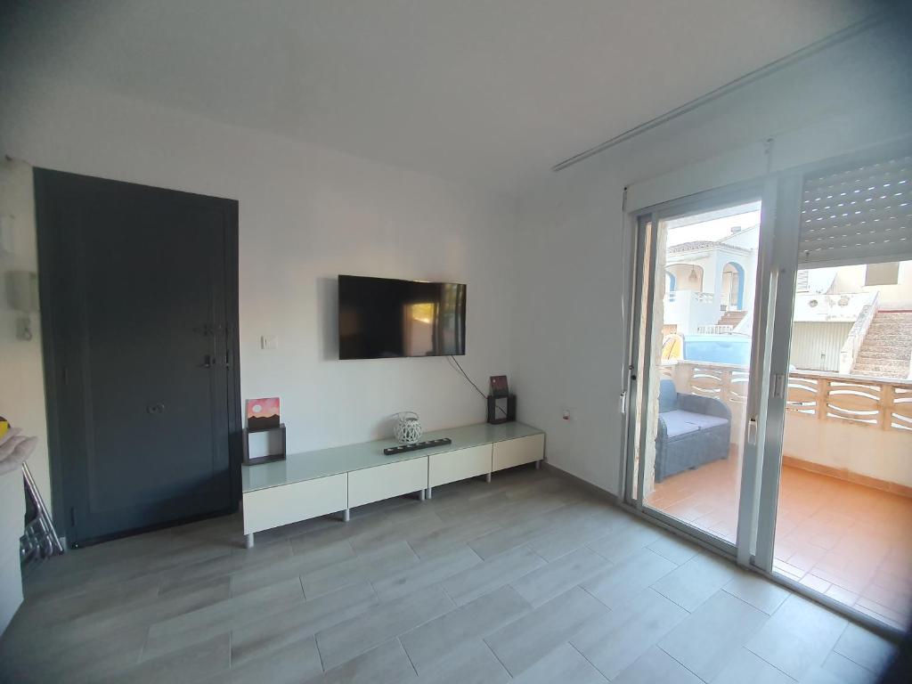 ein Wohnzimmer mit einem Tisch und einem TV an der Wand in der Unterkunft Apartamento a 100 metros de la playa in Piles