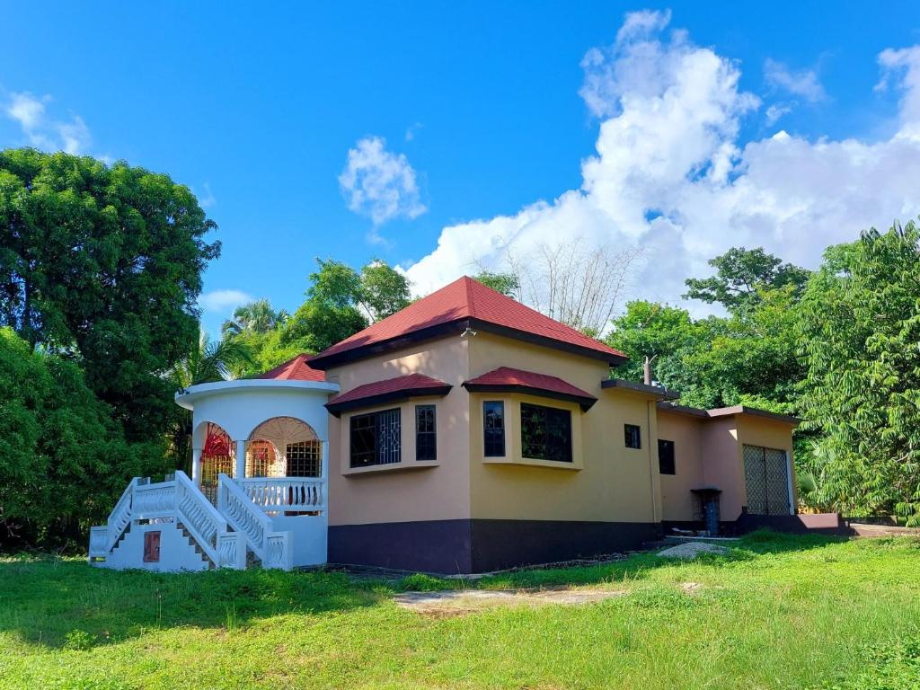 uma pequena casa amarela com um telhado vermelho em The Happy Retreat Villa in Belmont, Jamaica em Blue Hole