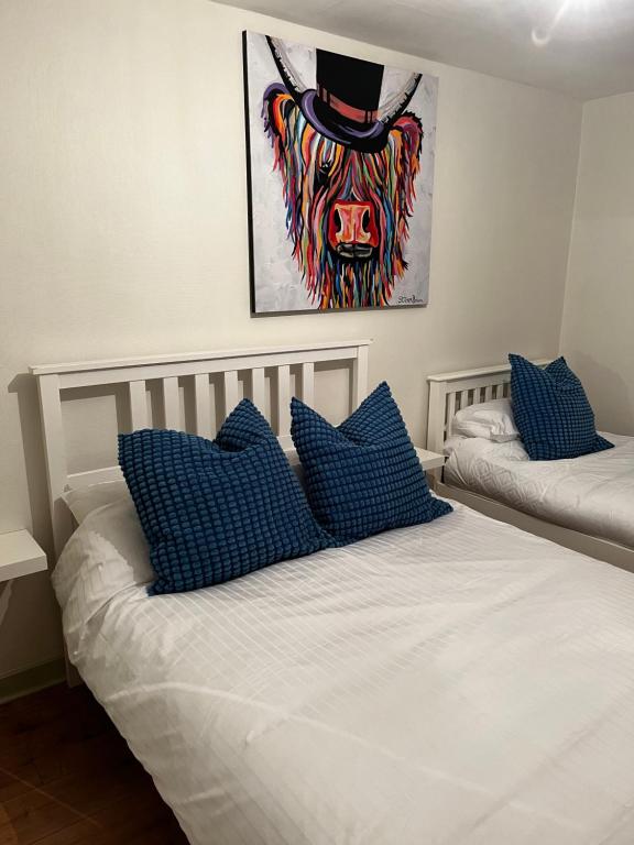 a bed with blue pillows and a cow with a top hat at The Chroma Cottage in Cock Hill