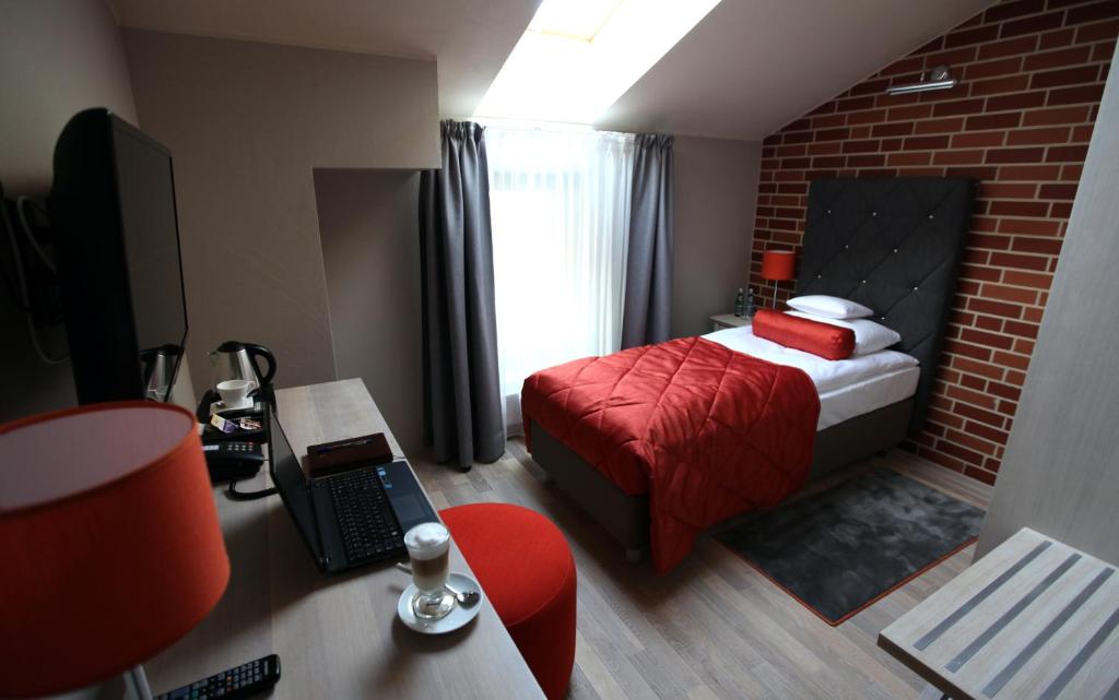 a bedroom with a red bed and a brick wall at Hotel Browar Kościerzyna in Kościerzyna