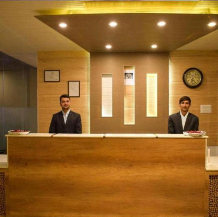 Due uomini in giacca e cravatta seduti alla reception. di Near Reliance Mall Hotel Green Land a Darjeeling