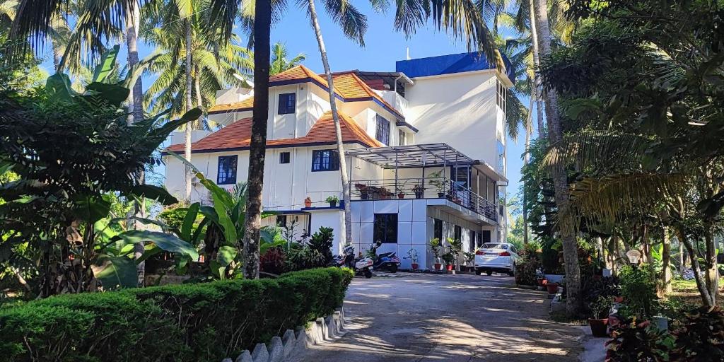 biały dom z palmami na ulicy w obiekcie Indeevaram Apartments w mieście Kovalam