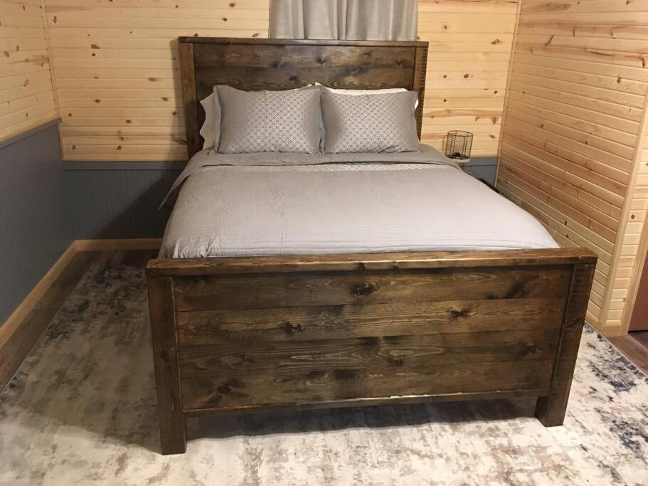 a bed with a wooden bed frame in a room at Caddy Corner has a hot tub just outside of town in French Lick