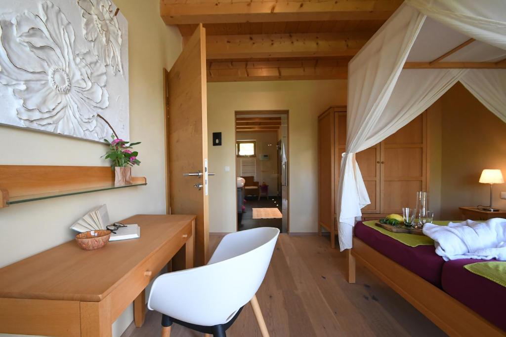 a bedroom with a bed with a white chair and a desk at Chalet Zauberberg in Zwiesel