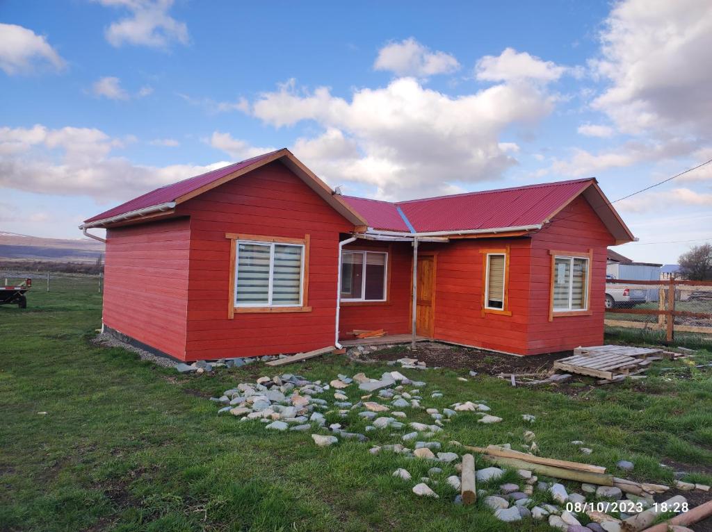 een rood huis met een rood dak in een veld bij Valle de la Luna in Coihaique Alto