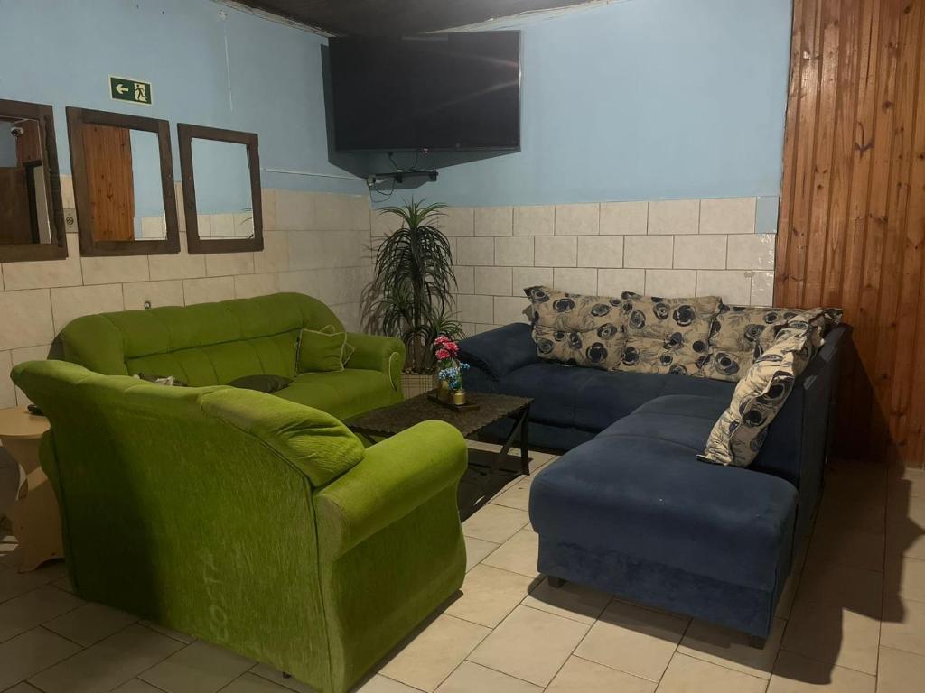 sala de estar con 2 sofás y TV en Pousada Neide, en São Gabriel