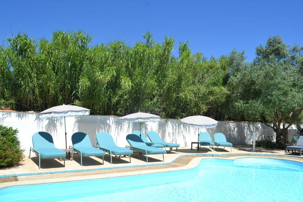 a pool with lounge chairs and umbrellas next to a pool at Atlantic Hôtel in Saint-Pierre-dʼOléron