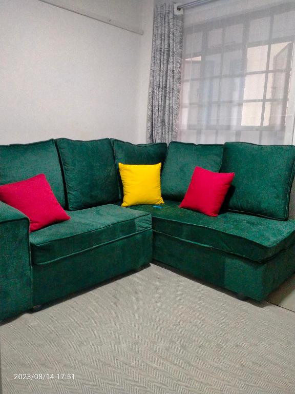 um sofá verde com quatro almofadas coloridas em Tranquil 2 homes em Nanyuki