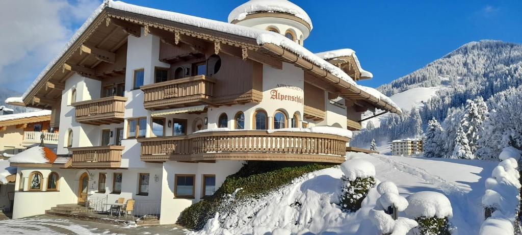 duży budynek pokryty śniegiem przed górą w obiekcie Appartements Alpenschlössl w mieście Oberau