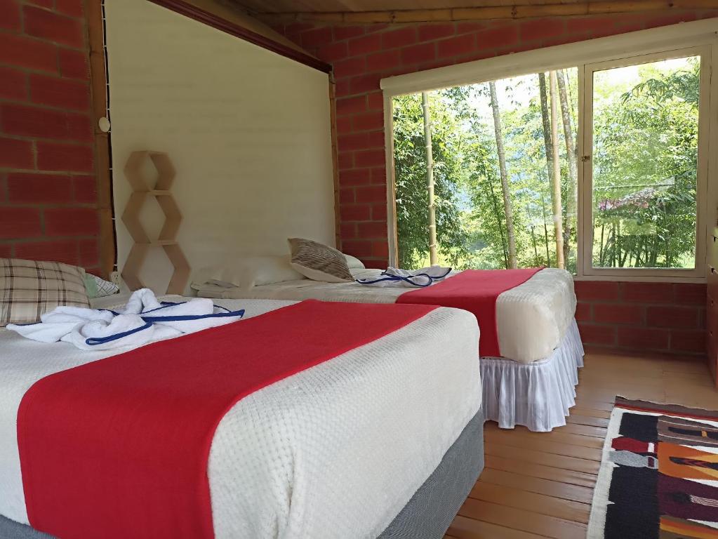 two beds with red and white blankets in a room at Green Bamboo Lodge in San Francisco de Borja