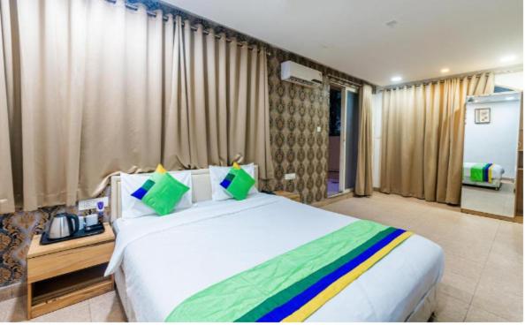 a bedroom with a large white bed with colorful pillows at HOTEL SWAASTIK in Pune