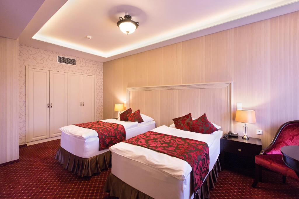 a hotel room with two beds and a chair at Hotel Dvorana in Karlovy Vary