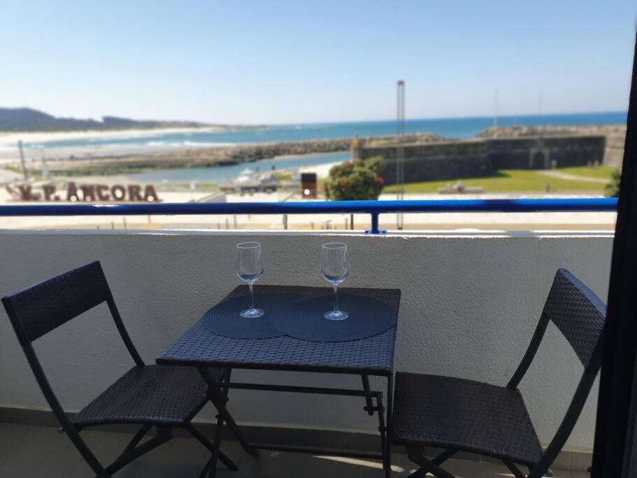 einen Tisch mit zwei Weingläsern auf dem Balkon in der Unterkunft Appartement de 90 m2 en 1ere ligne face a l'ocean in Vila Praia de Âncora