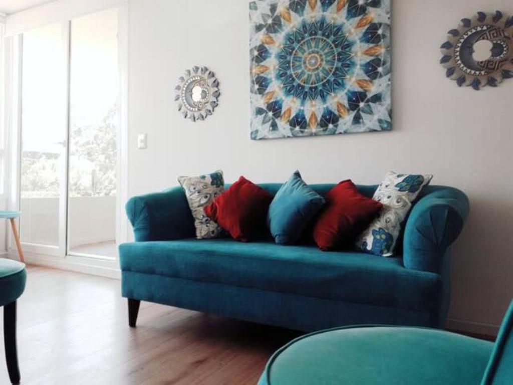 ein blaues Sofa mit Kissen im Wohnzimmer in der Unterkunft Departamento Mar, Bosque, Lomas de Papudo III, wifi in Papudo