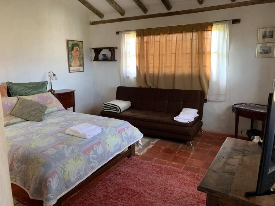 sala de estar con cama y sofá en Acogedora cabaña con bella vista a las montañas de Villa de Leyva, en Santa Sofía