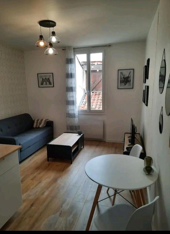 un salon avec un canapé bleu et une table dans l'établissement Le Black and White cosy studio Toulouse centre, à Toulouse