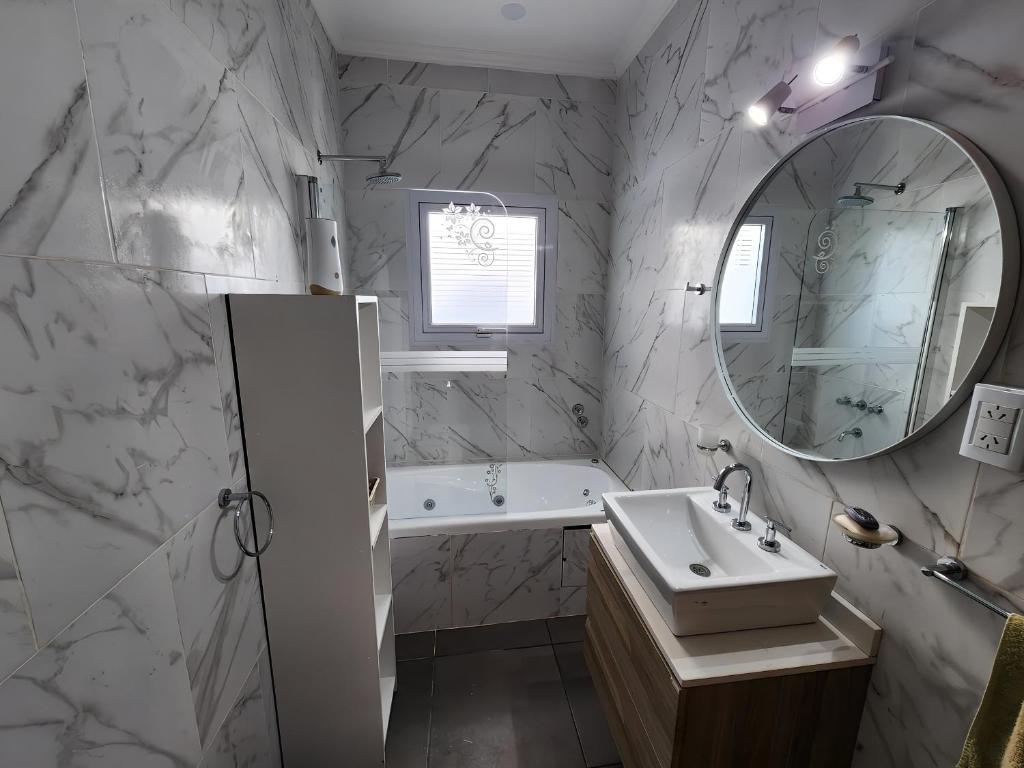 a bathroom with a sink and a tub and a mirror at Puesta de Sol Casa Quinta in Azul
