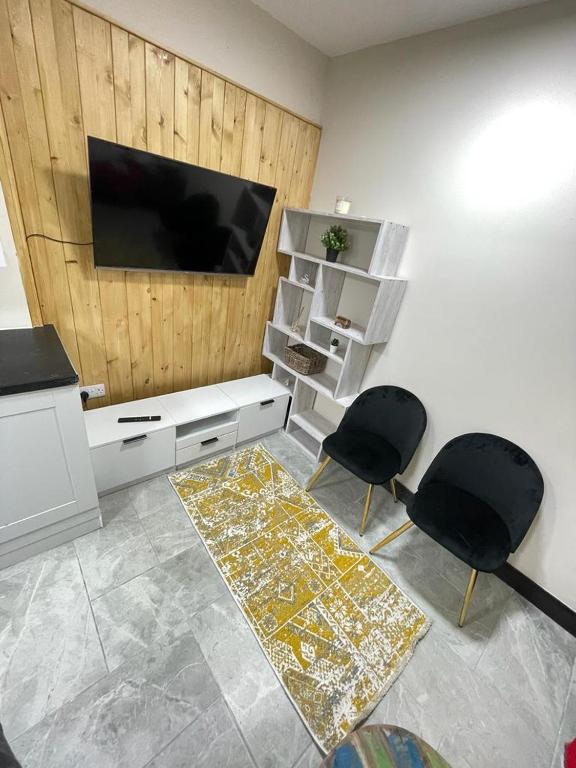 een woonkamer met 2 stoelen en een flatscreen-tv bij Airstaybnb in Manchester