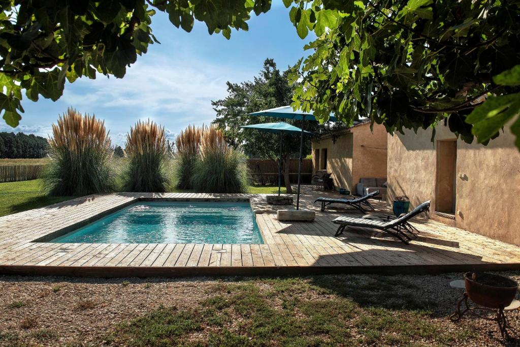 a swimming pool in a yard with a bench and an umbrella at Mas en Provence calme et sérénité piscine chaufffée in Verquières