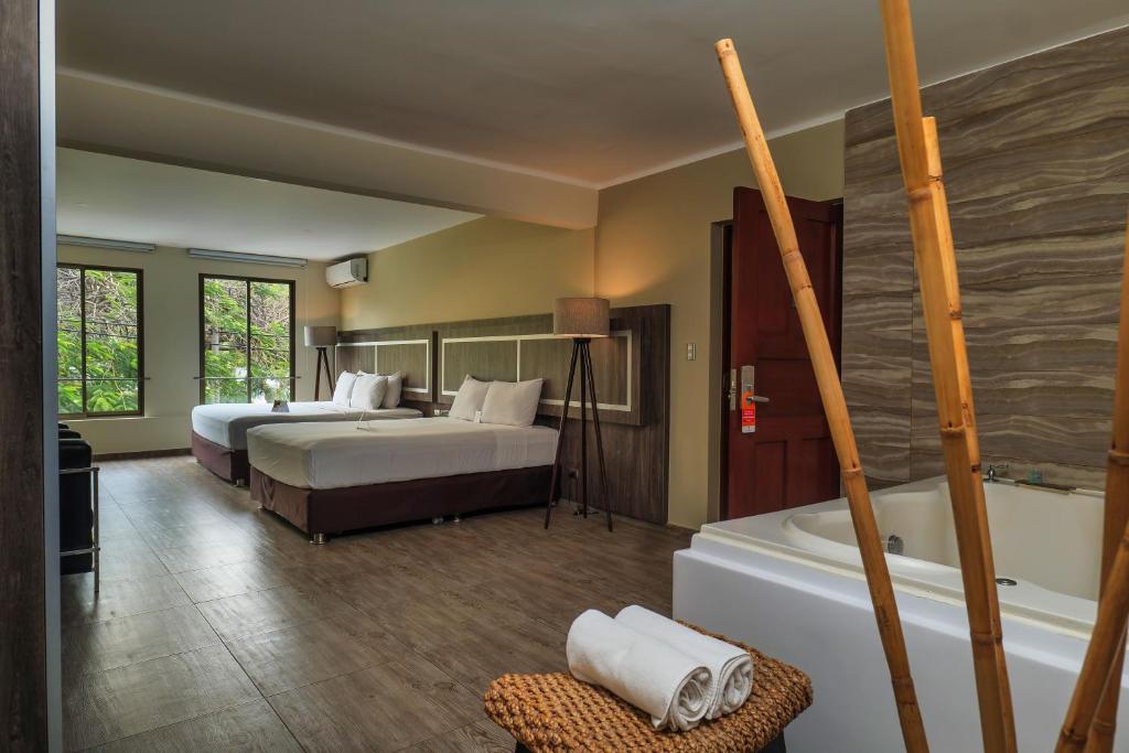 Habitación de hotel con 2 camas y bañera en Rado Hotel - Quintanas en Trujillo