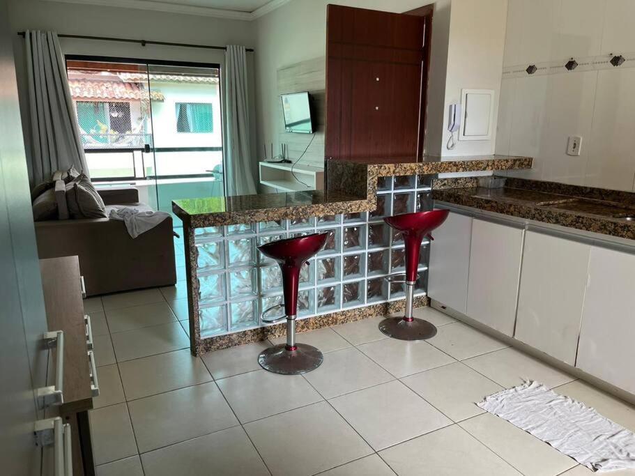 uma cozinha com dois bancos vermelhos no meio em Apartamento mobiliado em Porto Seguro
