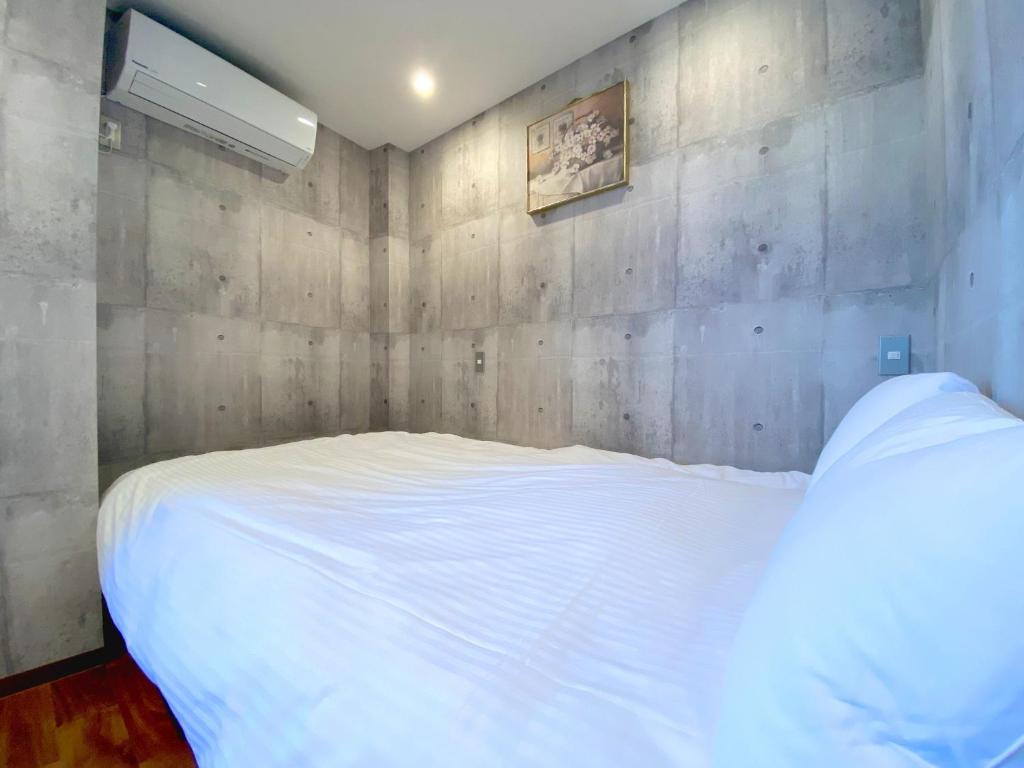 een slaapkamer met een wit bed en een muur bij Sakuraya Ryokan - Vacation STAY 51122v in Mongawa