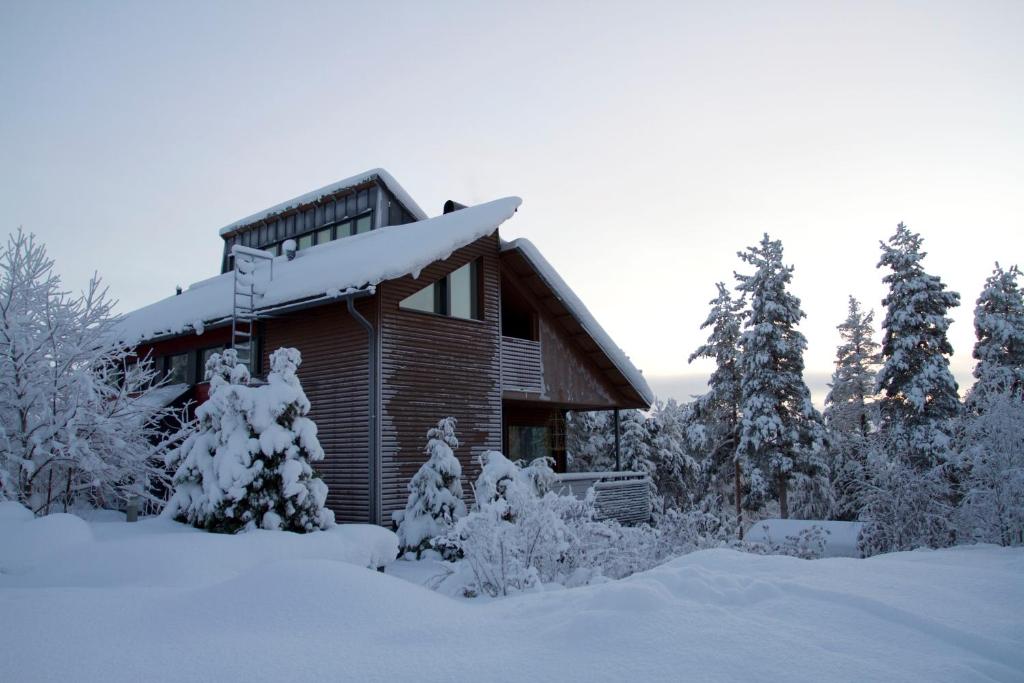 Cabaña de madera con nieve en el techo en Lux Villas by Arctic People, en Rovaniemi