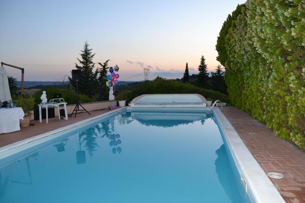 a large swimming pool with a hedge at Appartamento con piscina e tennis in Montespertoli