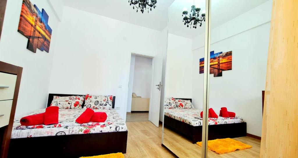 a bedroom with two beds with red pillows and a mirror at Designed like Home Apartment near Palas Mall in Iaşi