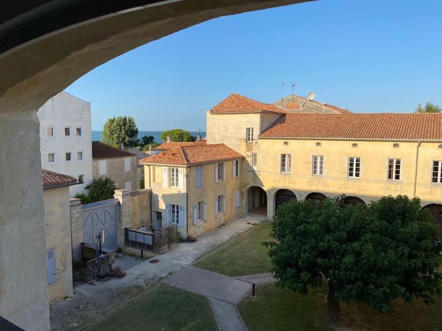 une vue depuis une arche d'une ville avec des bâtiments dans l'établissement Charmant appartement Château d'Oléron, au Château-dʼOléron