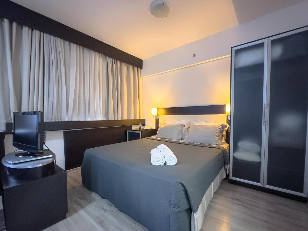 a hotel room with a bed with white shoes on it at Suíte Pátio Paulista 14 in São Paulo
