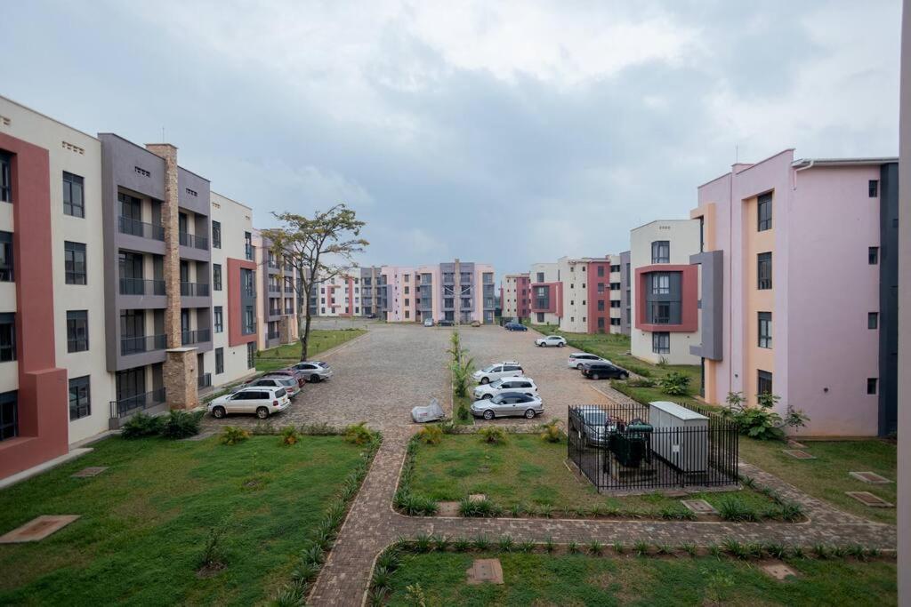 an apartment complex with cars parked in a parking lot at 1 Bedroom Lake View Apartment in Entebbe