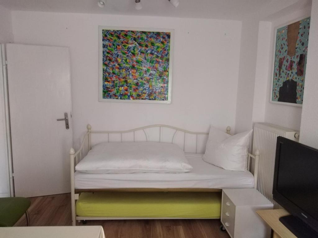 ein kleines Schlafzimmer mit einem Bett und einem Gemälde an der Wand in der Unterkunft Appertment im Garten in Worms