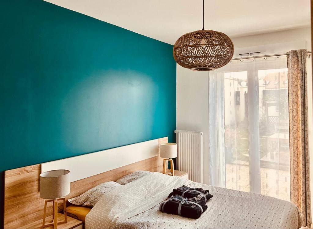 um quarto com uma parede azul e uma cama em T2 cosy- gare à pied- Disney-Paris- jardin privatif em Villenoy