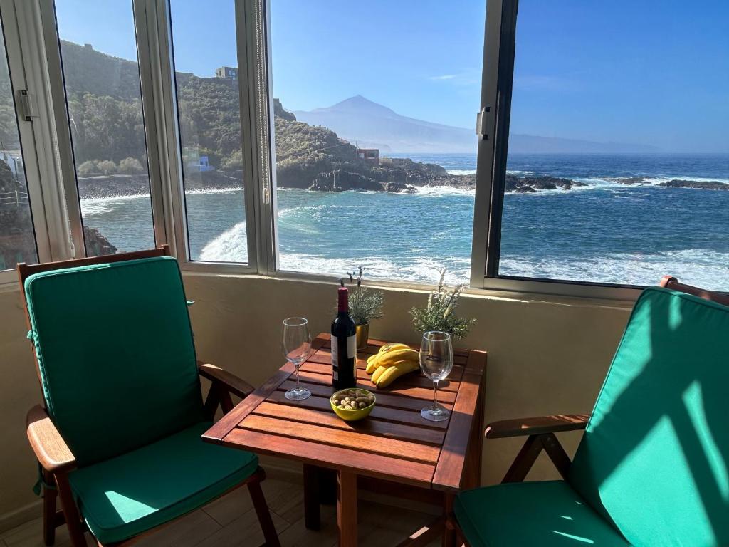 uma mesa com uma garrafa de vinho e duas cadeiras em The Waves em El Pris