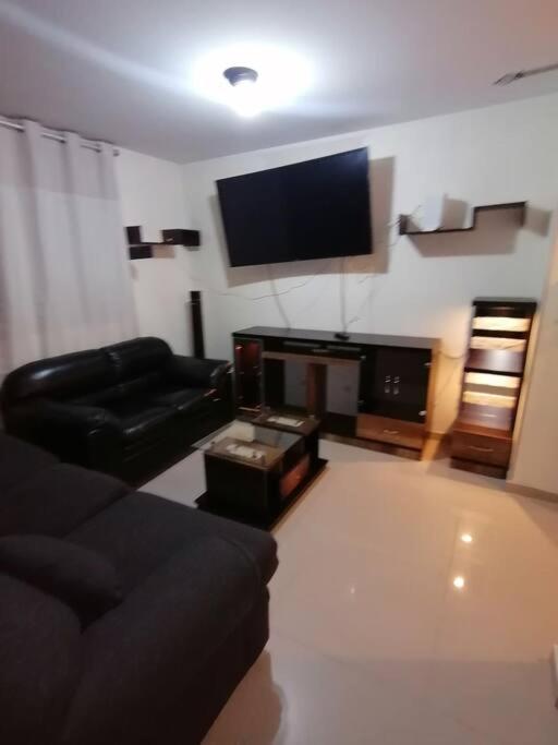 uma sala de estar com um sofá e uma televisão de ecrã plano em Mini departamento lujo em Lima