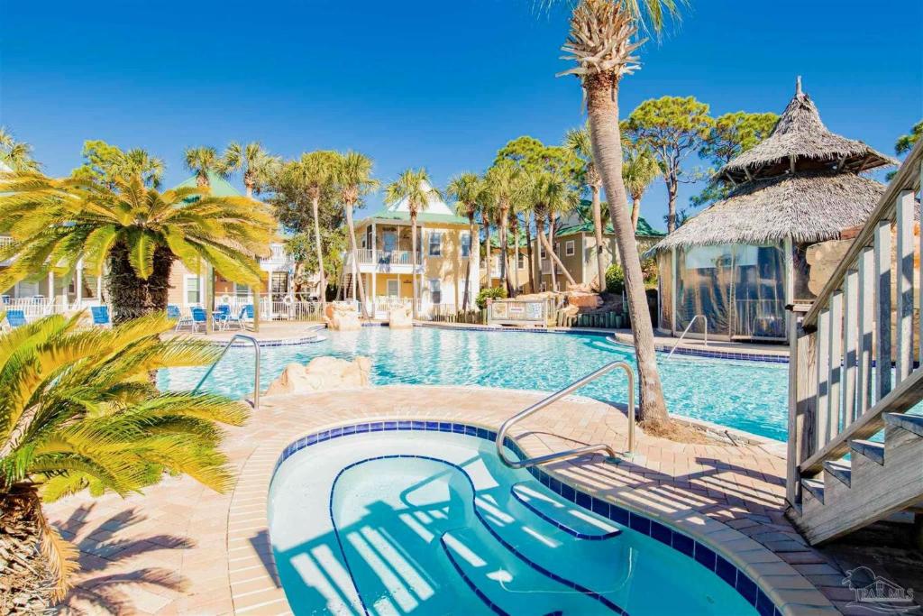 una piscina con palmeras y un complejo en Perdido Key Purple Parrot Resort, en Perdido Key