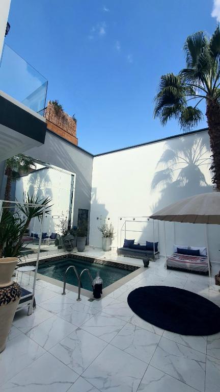 a house with a swimming pool and an umbrella at Riad VIP Bed & Breakfast in Marrakesh