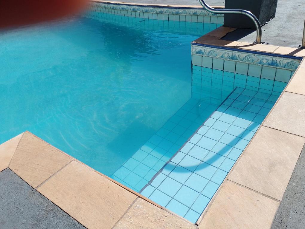 a swimming pool with blue tiles on the side of it at Mi Casa, Águas de São Pedro in Águas de São Pedro