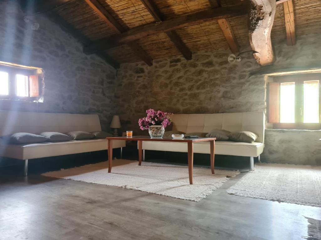 una habitación con 2 camas y una mesa con flores. en Casa di Pietra en Usellus